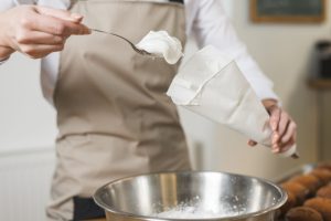 female-baker-filling-whipped-cream-white-icing-bag